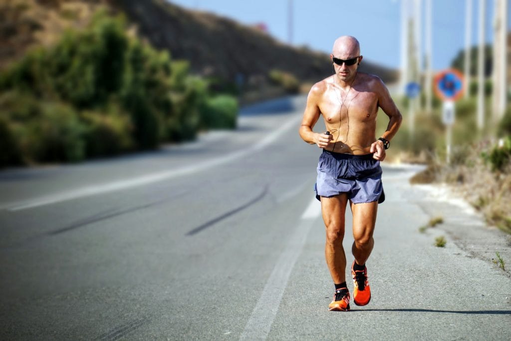 How to Build an Aerobic Base for Long-Distance Running: man running on open road with shirt off