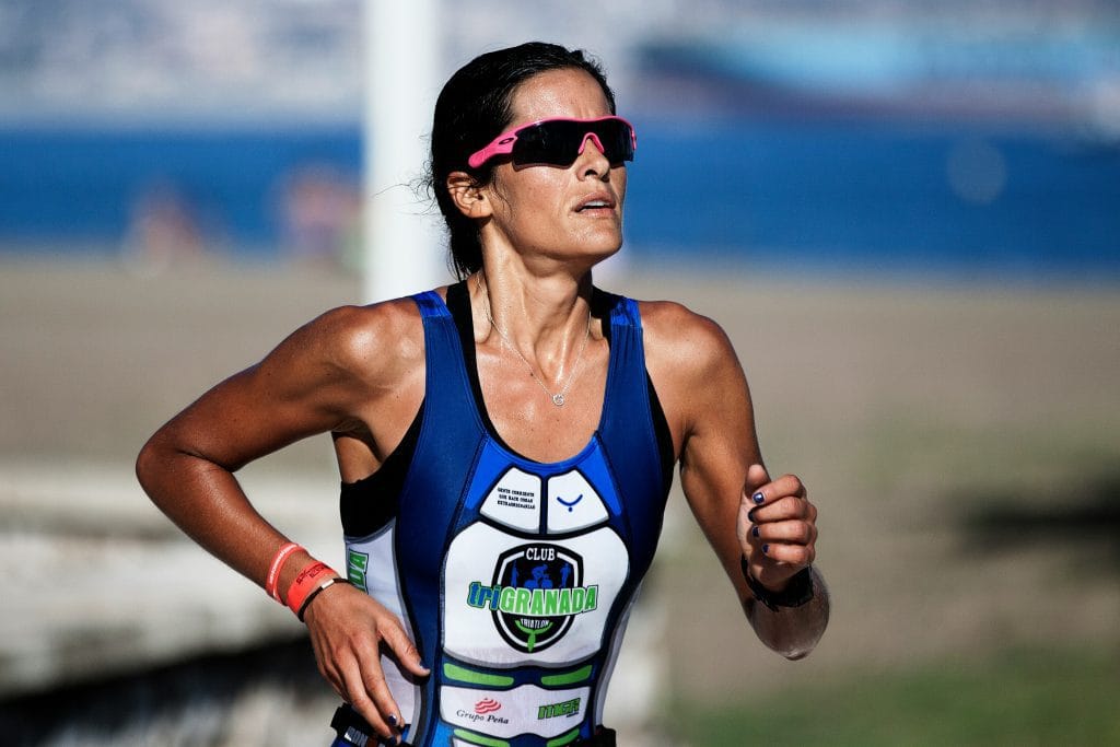 The Runner’s Mindset: Woman running with pink sun glasses on in blue running vest