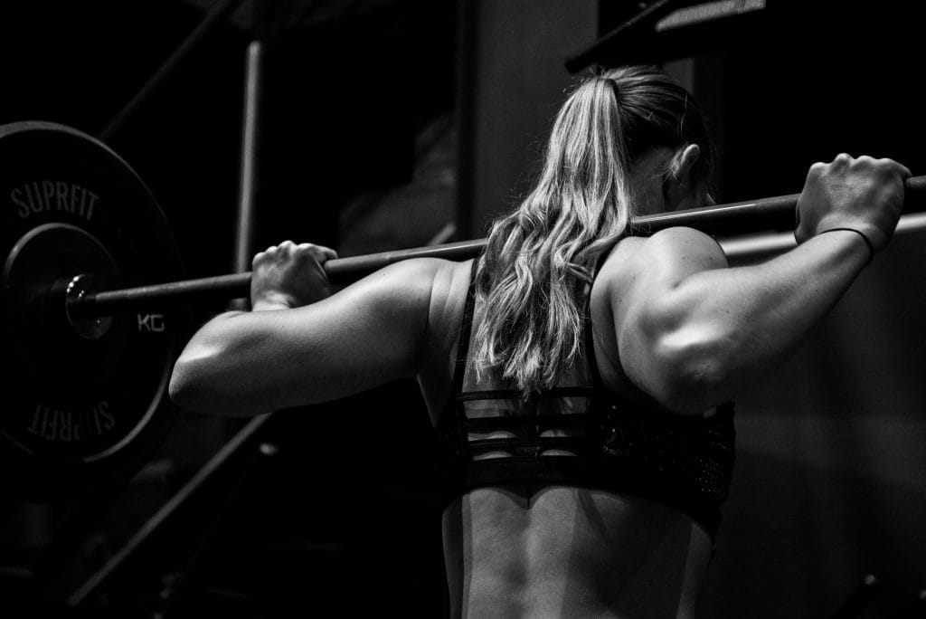 3-Day Strength Training Plan for Busy People New to Training: Woman squatting with barbell
